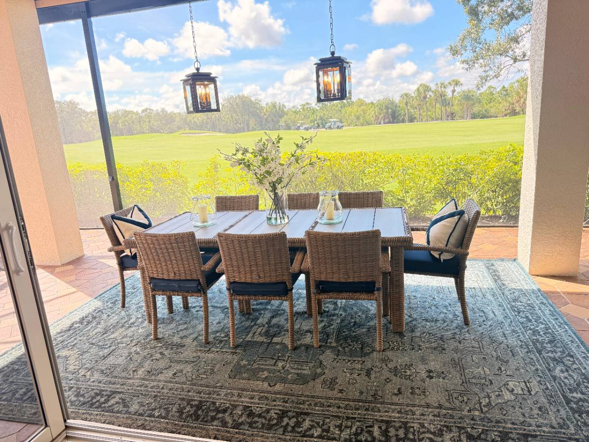 Screened lanai dining table set with flowers overlooking a golf course