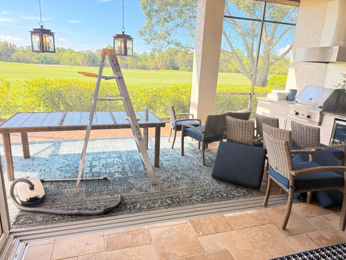 Outdoor lanai mid-clean with a ladder and cushions removed