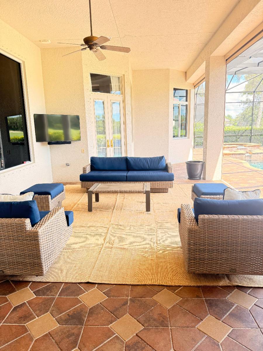 Covered lanai lounge with blue cushioned wicker furniture by a pool