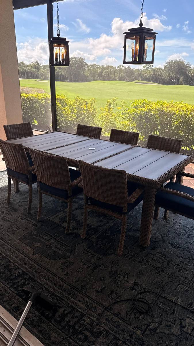 Outdoor dining table and chairs on a rug facing a golf course