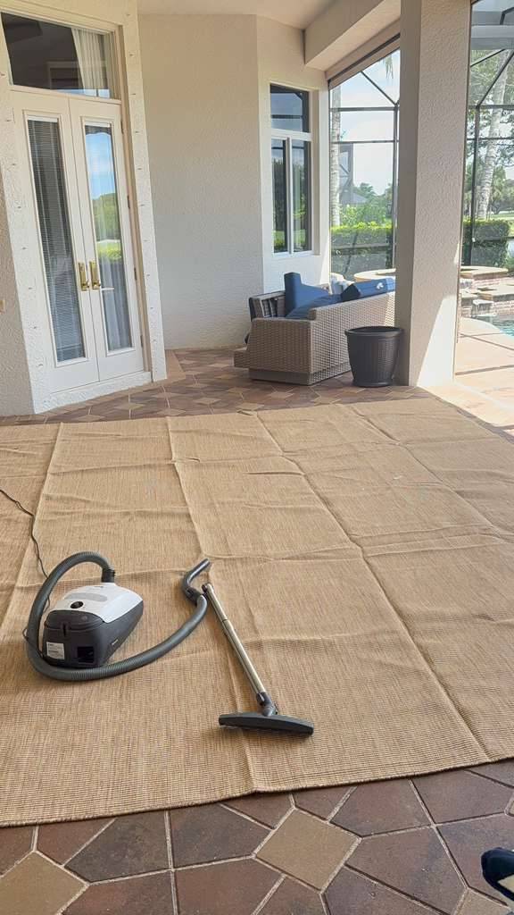 Vacuum on a large outdoor rug on a covered patio