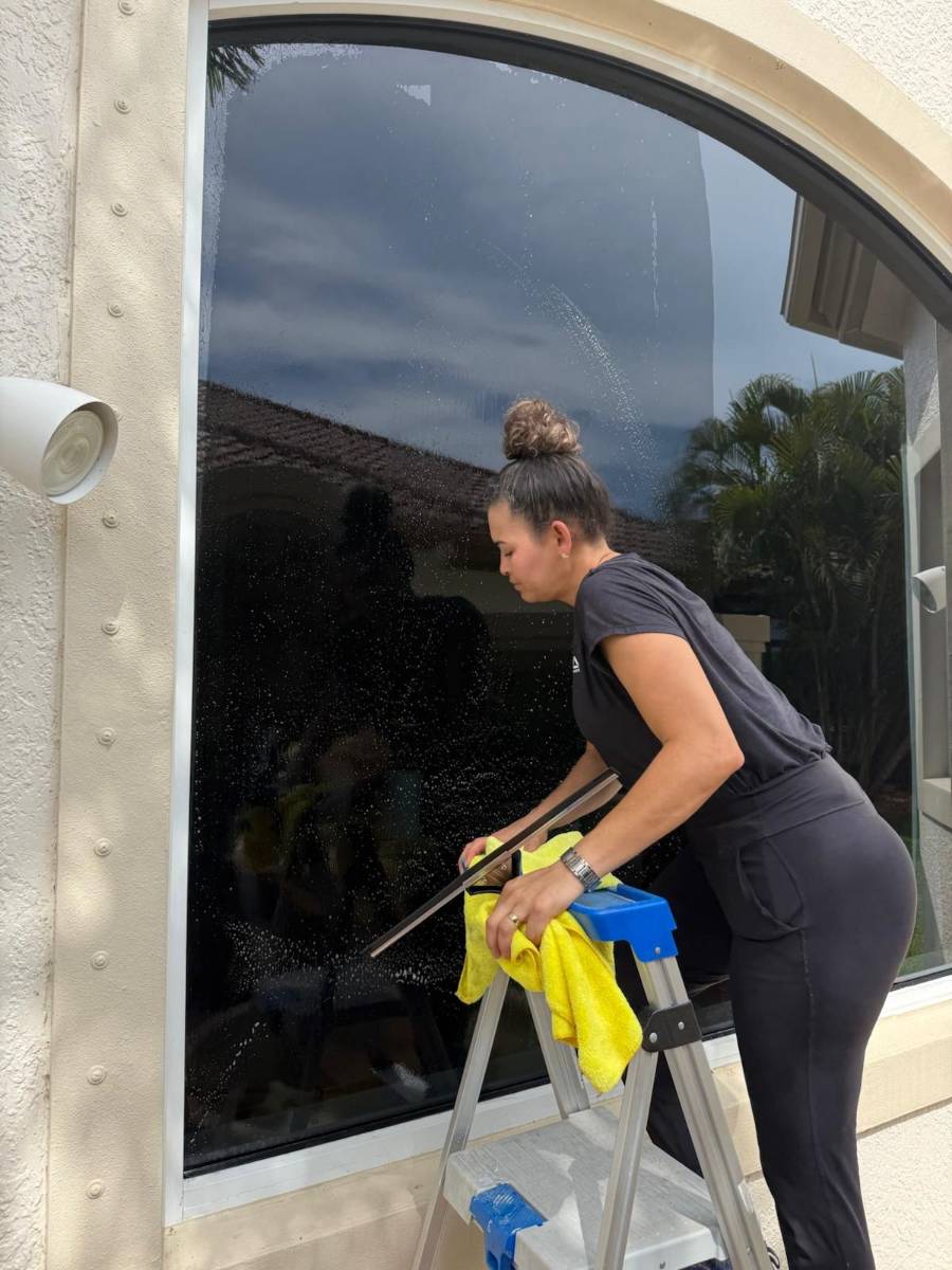 Rise and Shine team member squeegeeing an arched exterior window
