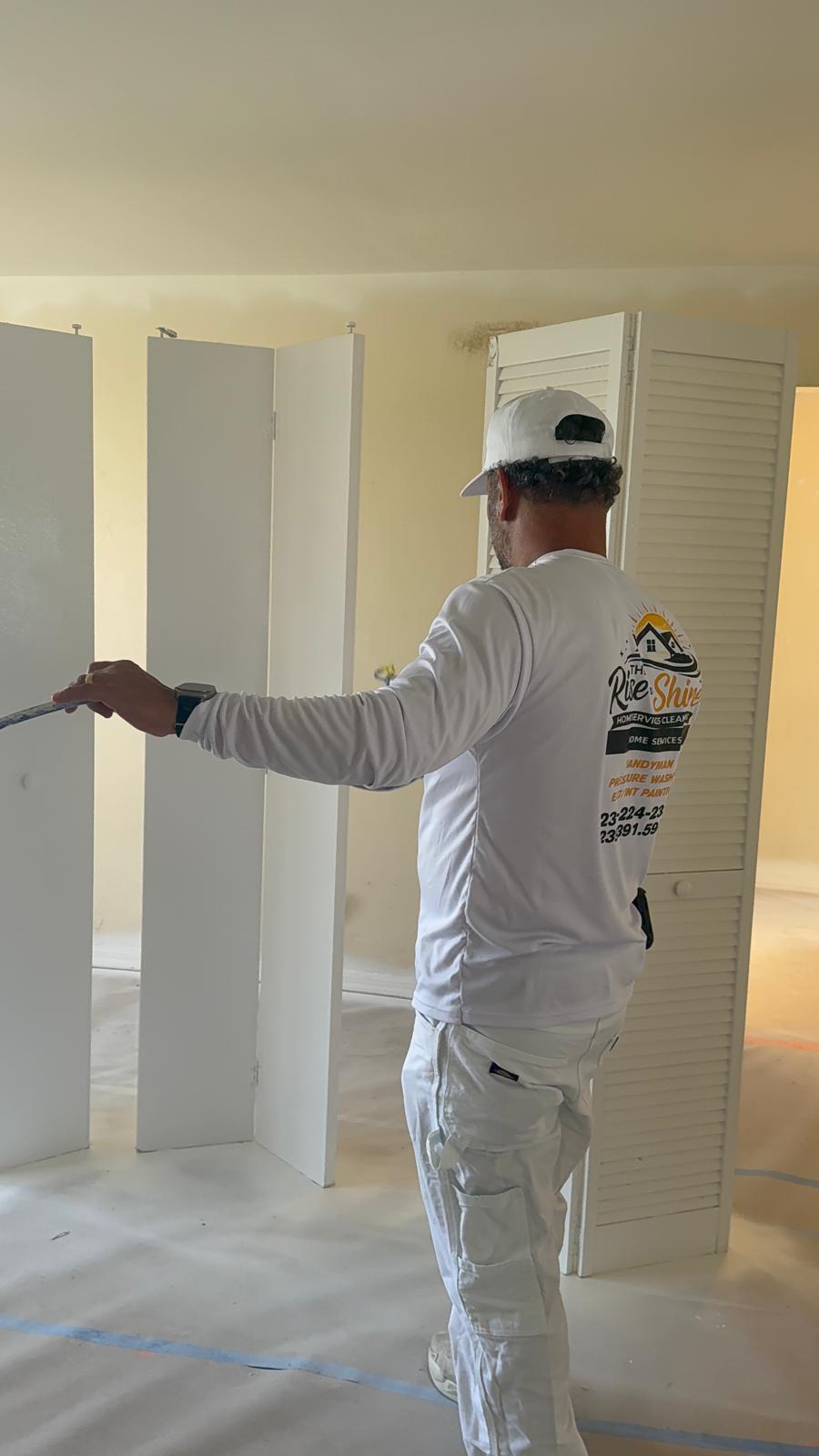 Painter spraying bifold closet doors white